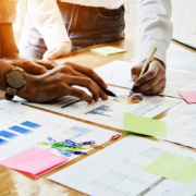 businessmen holding a pen pointing to paper graph on desk